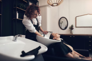 Full-service salon Aventura by Hair By Fleur showing a professional stylist providing a relaxing hair wash service to a client in a modern salon setting